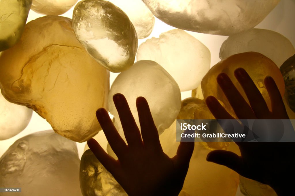 Childlike Wonder and Crystals: Child's hands on glowing stones Child's hands silhouetted against huge glowing crystals. Awe Stock Photo