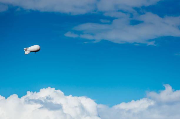 biały sterowiec z kamerą unoszącą się na niebie - spy balloon zdjęcia i obrazy z banku zdjęć