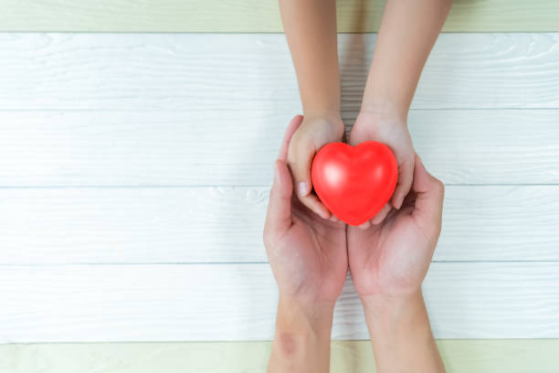 istock Father Day's and Mother's Day. Man holds his hands son supporting red heart. 1173256885
