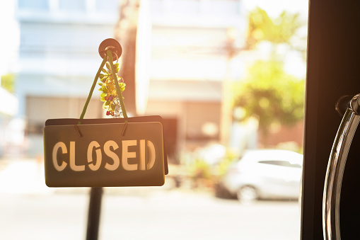 Closed sign hanging front of cafe with colorful bokeh light background. Business service