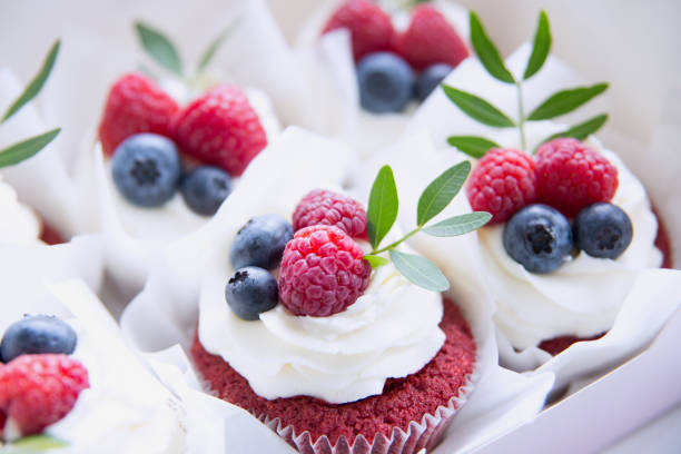 istock Appetizing cupcakes with white cream, raspberries and blueberries decorated with green leaves. 1173262688