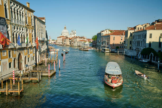 Venice, Italy - June 01, 2019: a ferry with tourists sailing in Grand Canal among historical buildings.
