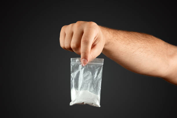 istock Male hand holds a plastic bag with cocaine on a blurred background, closeup. Social problem, drug addiction, death, addiction. Copy space. 1173265900