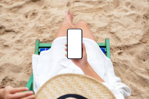 istock a woman holding black mobile phone with blank desktop screen while lying down on a beach chair 1173268364