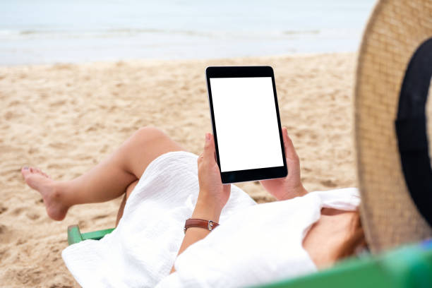 istock a woman holding a black tablet pc with blank desktop screen while lying down on a beach chair 1173268368