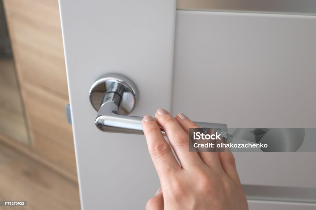 Weibliche Hand auf Metall-Türgriff. Modernes Interieur - Lizenzfrei Tür Stock-Foto