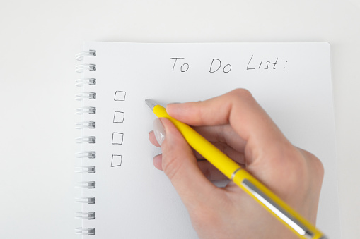 Mujer escribiendo la pluma amarilla de la lista de tareas pendientes. Planificación conceptual y autogestión. Vista superior, arriba photo