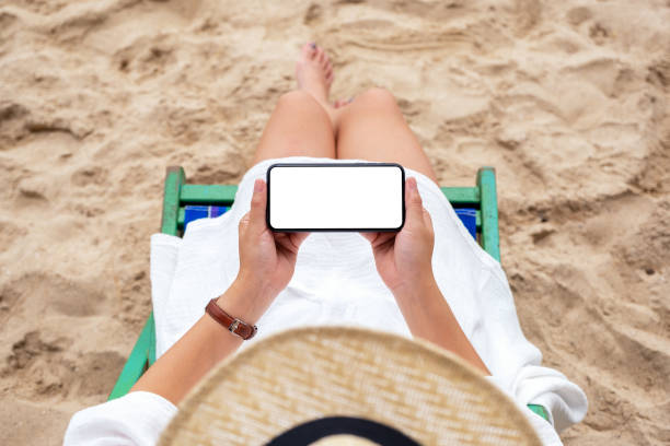 istock a woman holding black mobile phone with blank desktop screen while lying down on a beach chair 1173272580
