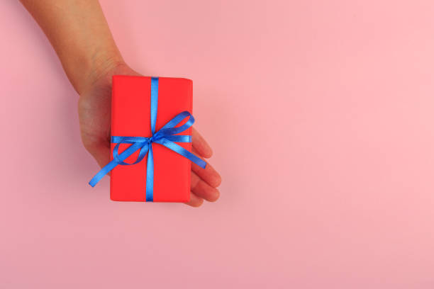 istock gift in female hands on a colored background top view. 1173274367