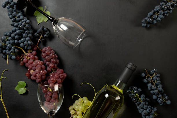 istock Bottle, two wine glasses, fresh grapes and leaves on black background. Flat lay, top view, copy space. Wine bar, winery, wine tasting concept 1173275595