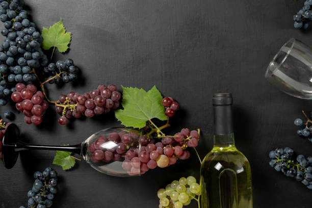 istock Bottle, two wine glasses, fresh grapes and leaves on black background. Flat lay, top view, copy space. Wine bar, winery, wine tasting concept 1173275878