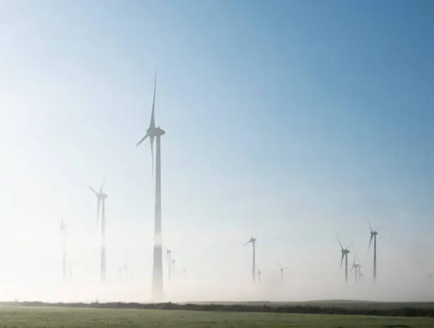 wind turbines in green meadow near aurich in german lower saxony on misty morning in august