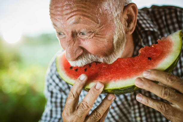 istock Mature man biting fresh watermelon outdoors. 1173279982