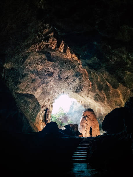 istock Human silhouette stands inside the cave with light coming from the ceiling 1173280253