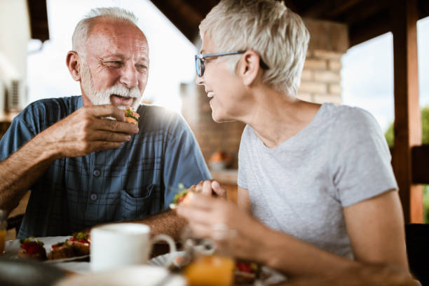 Happy mature couple talking while having breakfast on a balcony.