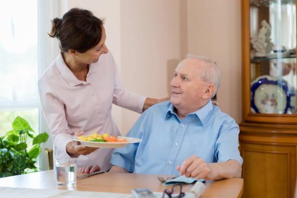 在宅介護者 – シニア男性を助ける女性 - senior adult nursing home eating home interior ストックフォトと画像