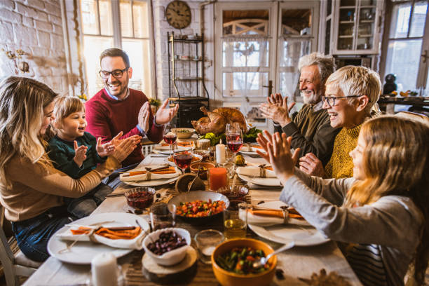 istock Happy extended family applauding during Thanksgiving meal at dining table. 1173282788