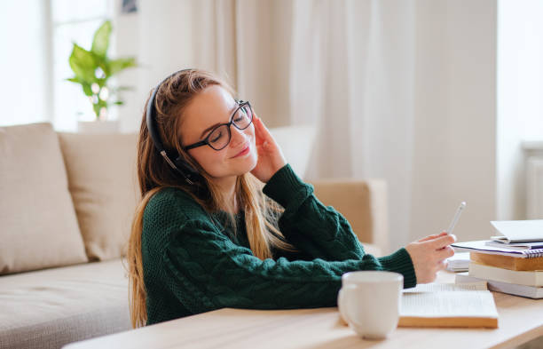 istock A young female student sitting at the table, using headphones when studying. 1173289710