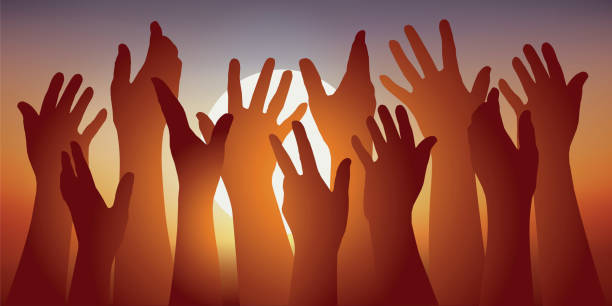 istock Symbol of union with several hands raised in front of a setting sun. 1173290854