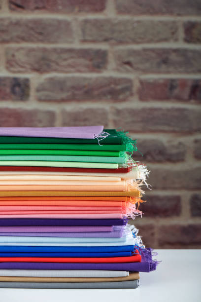 istock Stack of colorful fabrics on brick wall background, space for text 1173293153