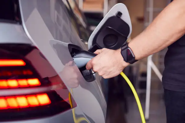 Photo of Close Up Of Hand Attaching Power Cable To Environmentally Friendly Zero Emission Electric Car