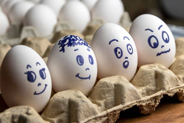 istock Lovely eggs in cardboard box. Eggs with emotions. White eggs in cardboard box with different faces painted on them. Boys and girl. 1173293369