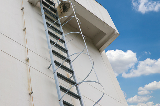 Steel stairs are installed on the side of the building and supported by a back support. Steel ladder and back support.