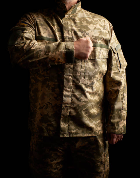 o soldado ucraniano vestiu-se no uniforme está na obscuridade e põr sua mão direita a seu coração - pants green camouflage men - fotografias e filmes do acervo