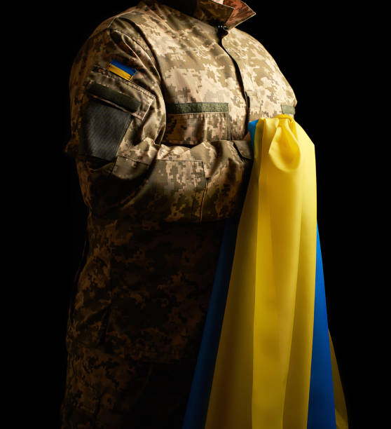 o soldado ucraniano prende em sua mão a bandeira amarelo-azul do estado, ele pressionou sua mão a sua caixa - pants green camouflage men - fotografias e filmes do acervo