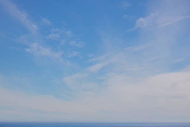 istock Soft whispy clouds on a blue sky over the ocean. 1173301560
