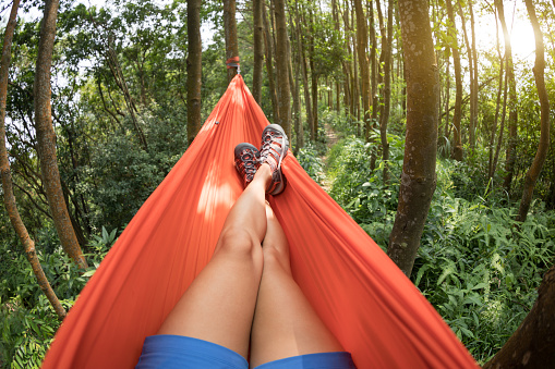 Woman relaxing in hammock with smartphone in rainforest