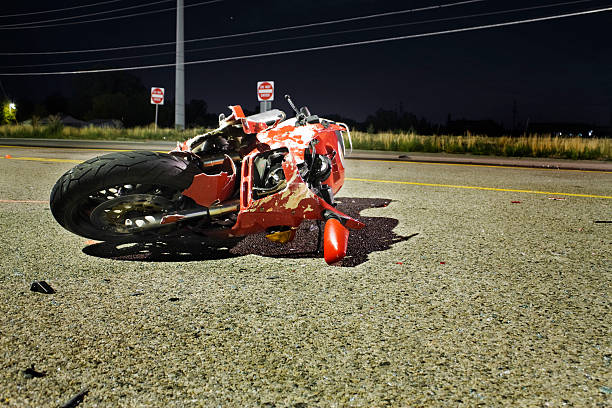 Close-up of wrecked red motorcycle on side of road Crash scene.  Red motorcycle laying on its side on the street.  Illuminated by a overhead street light. misfortune stock pictures, royalty-free photos & images