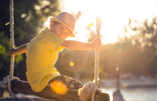Small boy swinging on a swing at sunset
