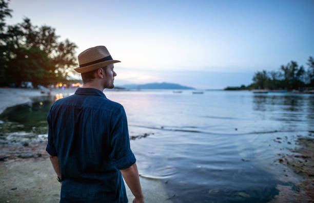 istock Man relaxing near sea at sunset 1173319986