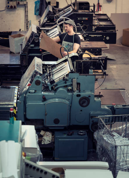 homem da impressora na oficina da indústria de impressão - young men printing plant printing press factory - fotografias e filmes do acervo