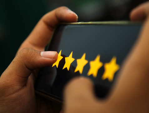 manos atractivas que muestran la calificación de cinco estrellas en un teléfono inteligente photo