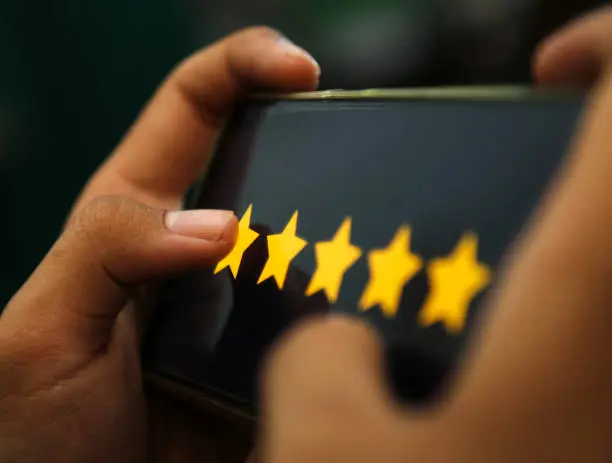 Photo of attractive hands showing five stars rating on a smart phone