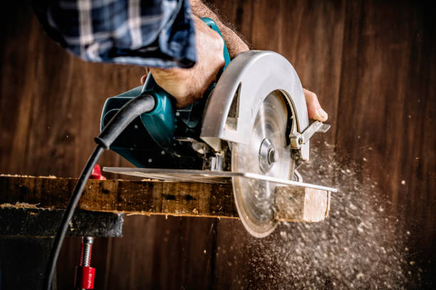 istock Male carpenter using electric circular saw in home workshop with wood chips flying 1173326476