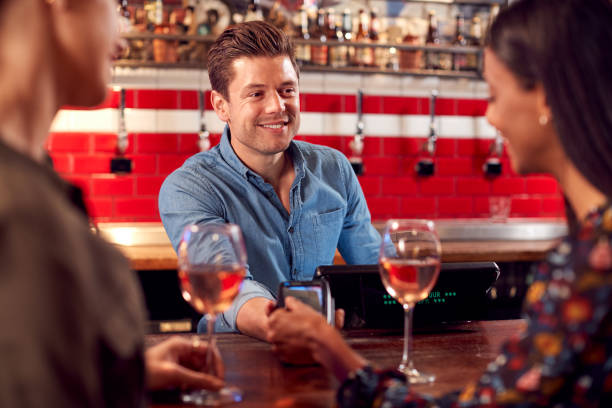 istock Woman Paying Barman For Drinks At Bar After Work Using Contactless Card 1173330862
