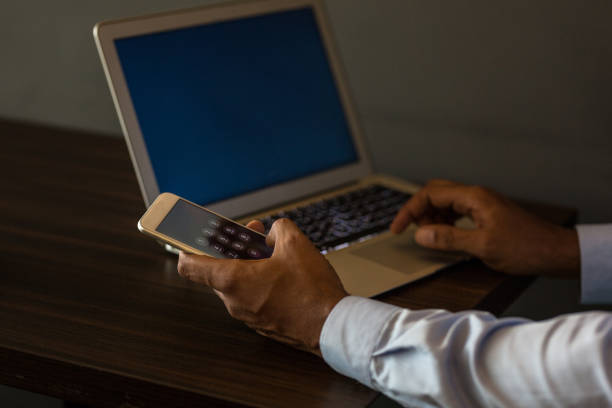 istock Man holding mobile phone and using laptop 1173332181