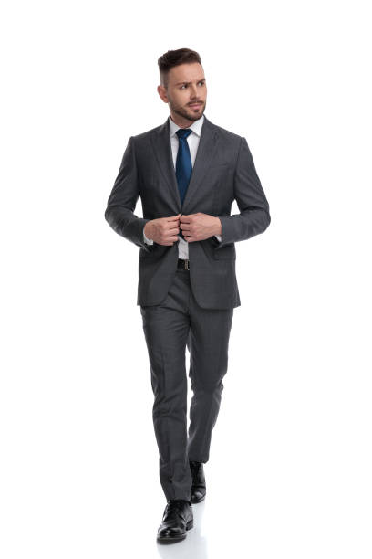 istock young businessman walking and closing his coat while looking away 1173333009