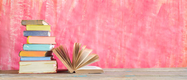 istock Open Book and stack of multicolored hardback books, reading education, literature,book fair concept. Panoramic format, good copy space 1173336749