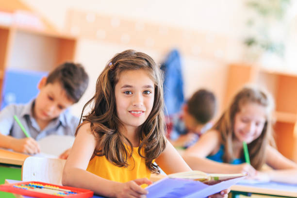 istock Schoolgirl reading a book in the classroom 1173336861