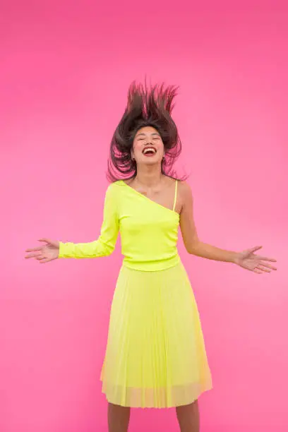 Asian young model woman jumping hair  yellow dress on pink background
