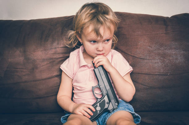 Child is playing with parents pistol - safety concept Child is playing with parents pistol - safety and accident concept baby gun stock pictures, royalty-free photos & images