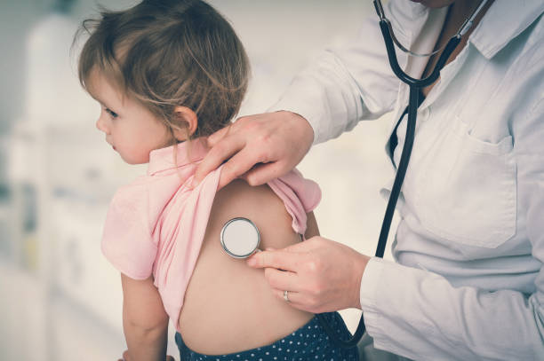 Pediatrician doctor examining a little girl by stethoscope stock photo