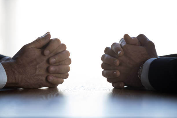 istock Close up of businessmen sit at table with hands clenched 1173338406