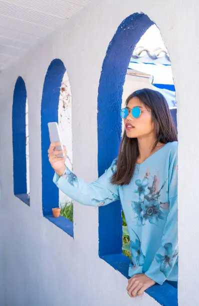 Asian tourist selfie photo in Mediterranean arch white arcade and blue sunglasses