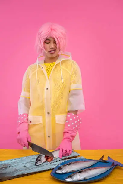 Asian Fishmonger woman with humor in pink and yellow with mackerel fish and knife