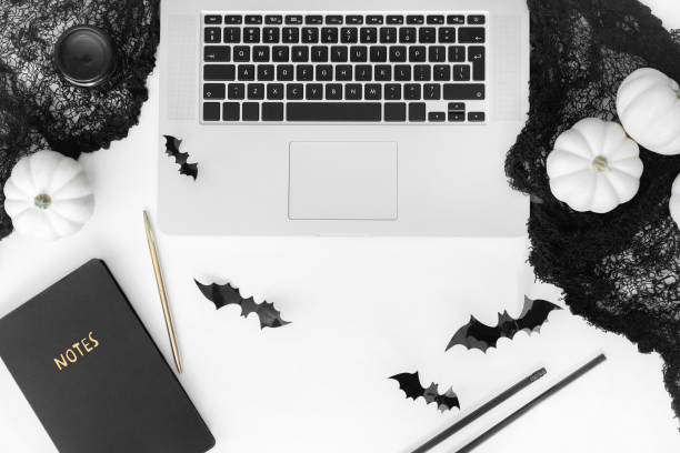 istock Halloween styled flat lay with laptop and decorative accessories top view on white table. 1173339016
